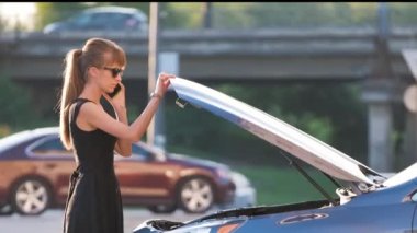 Kaputu açık bir şekilde arabasının yanında duran çaresiz kadın yardım için yol servisini arıyor. Genç bayan sürücünün aracıyla ilgili sorunları var