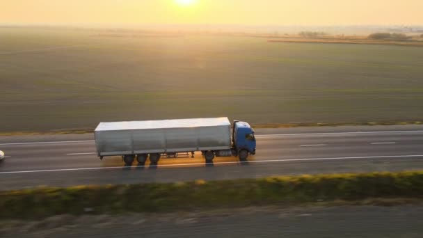 Flygfoto av semi-truck med last släpvagn kör på motorvägen transporterar varor på kvällen. Leveranstransport och logistikkoncept — Stockvideo