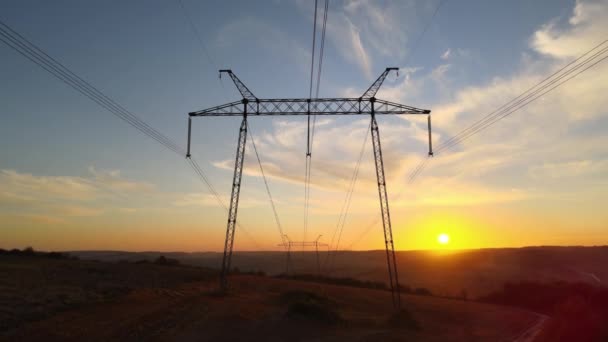 Dark silhouette of high voltage tower with electric power lines at sunrise. Transmission of electric energy concept — Stock Video