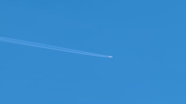 Entfernte Passagierflugzeuge fliegen in großer Höhe bei klarem blauen Himmel und hinterlassen weiße Rauchspuren von Kondensstreifen. Lufttransportkonzept — Stockvideo