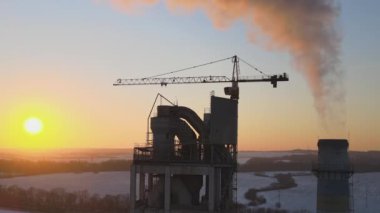 Gün batımında endüstriyel üretim alanında yüksek beton yapılı çimento fabrikası kulesinin havadan görüntüsü. Üretim ve küresel sanayi kavramı