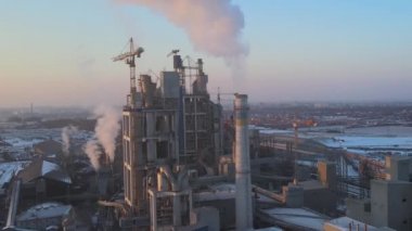 Yüksek beton fabrika yapısı ve sanayi bölgesinde kule vinçleri olan çimento fabrikasının hava görüntüsü. Sera gazı havayı kirletiyor. Üretim ve küresel sanayi kavramı