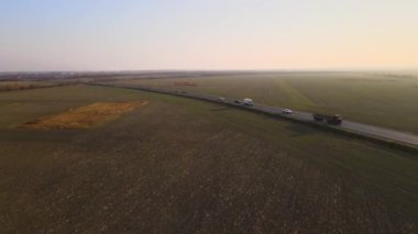 Gün batımında hızlı giden arabalarla şehirlerarası yol manzarası. Akşamları otoban trafiğinin insansız hava aracı görüntüsü