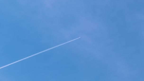遠くの旅客機は白い雲が後ろの輪郭の煙の跡を残す青い空の高い高度で飛んでいる。航空旅行の概念 — ストック動画