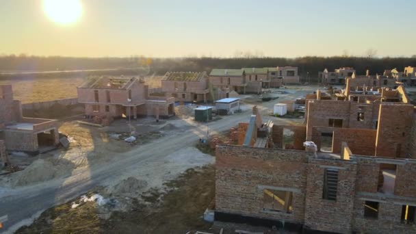 Flygfoto av nya hem med tegelväggar under uppbyggnad i förorter på landsbygden. Utveckling av fastigheter i en modern stadsförort — Stockvideo