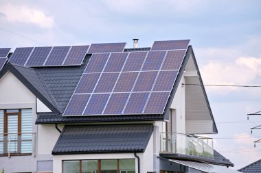 Banliyö bölgesinde temiz ekolojik elektrik enerjisi üretmek için güneş fotovoltaik panellerle kaplı çatısı olan bir ev. Özerk konut kavramı