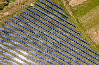 Temiz ekolojik elektrik enerjisi üretmek için birçok sıra güneş fotovoltaik paneli bulunan sürdürülebilir büyük elektrik santralinin havadan görünüşü. Sıfır emisyon kavramı ile yenilenebilir elektrik