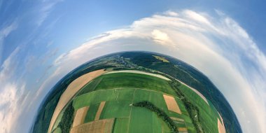 Dünya gezegeninin yüksek irtifasından yeşil ve sarı ekili tarım tarlaları ile aydınlık yaz gününde ekinlerin büyümesi.
