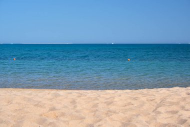 Mavi deniz suyunun yüzeyi ve küçük dalgalı dalgaların sarı kumsala çarptığı deniz burnu. Seyahat ve tatil kavramı