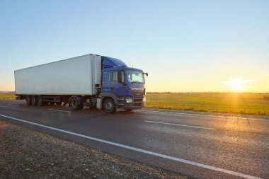 Kargo karavanı olan yarı kamyon akşam vakti otobanda mal taşır. Teslimat ulaşım ve lojistik kavramı
