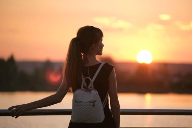 Yalnız genç bir kadın gölün kıyısında tek başına sıcak akşamın tadını çıkarıyor. Doğada refah ve rahatlama kavramı