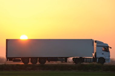 Kargo karavanı olan yarı kamyon akşam vakti otobanda mal taşır. Teslimat ulaşım ve lojistik kavramı