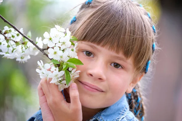 Glad barn flicka leker i vår trädgård njuter söt doft av vita körsbär träd blommande blommor på solig dag — Stockfoto