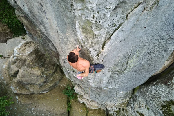 Starker männlicher Bergsteiger, der die steile Wand des felsigen Berges erklimmt. Sportler überwinden schwierige Strecke. Engagement im Extremsport Hobby-Konzept — Stockfoto