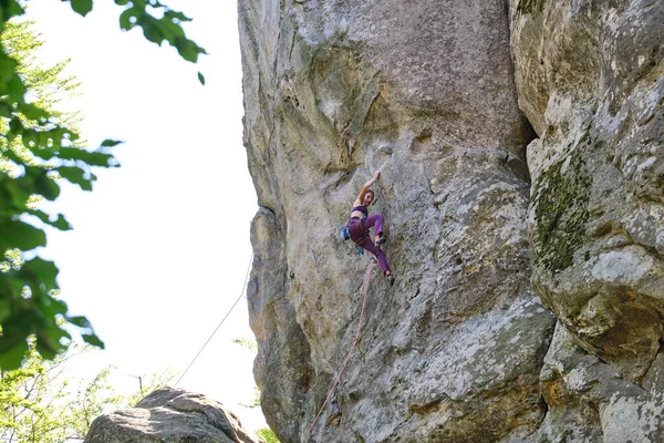 岩の多い山の急な壁を登る少女登山を決定した。難しいルートを克服するスポーツ女性。極端なスポーツやロッククライミングの趣味の概念に従事 — ストック写真