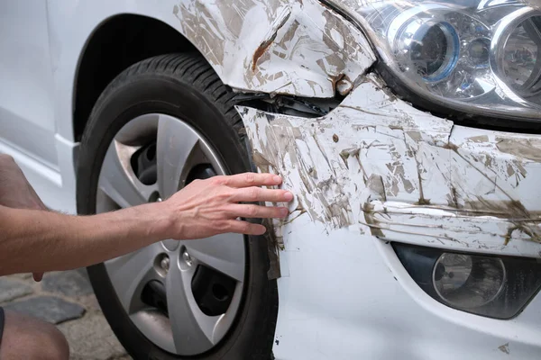 司机用手检查停在城市街道一侧的带损坏挡泥板的凹凸不平的汽车。道路安全和车辆保险概念 — 图库照片