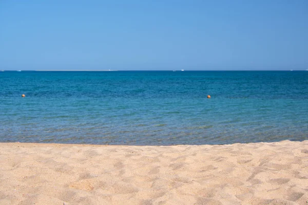 Mavi deniz suyunun yüzeyi ve küçük dalgalı dalgaların sarı kumsala çarptığı deniz burnu. Seyahat ve tatil kavramı