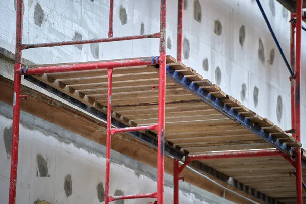 改装中の建物のファサードは、建設足場フレームで動作します。エネルギー効率の良い家のための発泡スチロールシートと壁断熱材 — ストック写真
