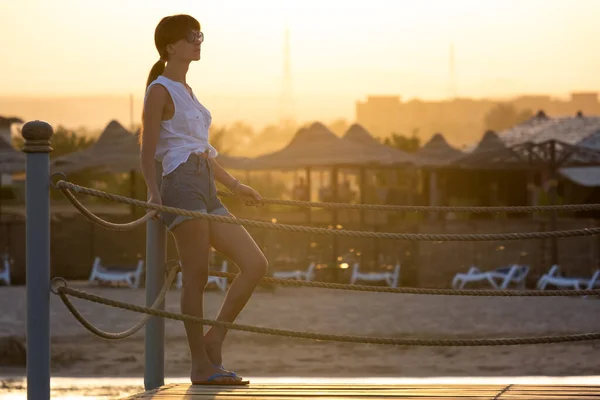 Giovane turista donna in abiti casual godendo di calda serata di sole sulla riva del mare. Vacanze estive e concetto di viaggio — Foto Stock