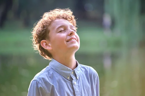 Giovane bambino felice ragazzo rilassante nel parco estivo. Ragazzo positivo che si gode l'estate all'aria aperta. Concetto di benessere infantile — Foto Stock