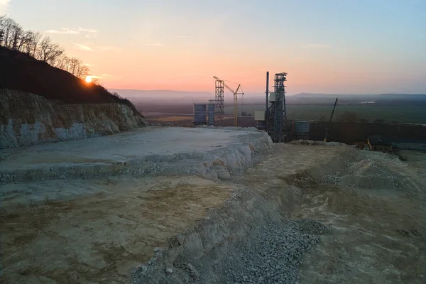 Цементный завод на открытой шахте добычи строительных песчаных каменных материалов. Копание ресурсов гравия в карьере на закате — стоковое фото