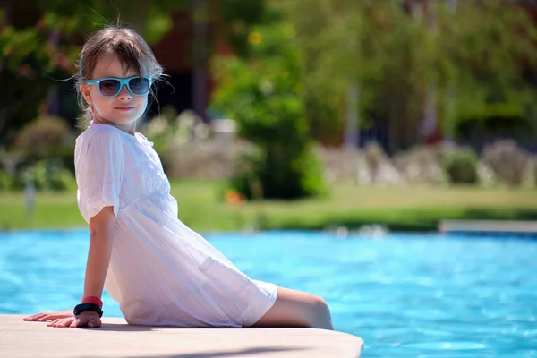 Menina feliz em vestido branco relaxante no lado da piscina no dia ensolarado de verão — Fotografia de Stock