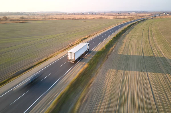 Vista aérea de semi-caminhão em movimento rápido desfocado com reboque de carga dirigindo em mercadorias de transporte rodoviário à noite. Conceito de transporte e logística de entrega — Fotografia de Stock