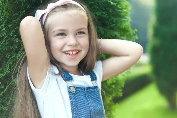 Portret ślicznej dziewczynki stojącej na świeżym powietrzu w letnim parku uśmiechającej się szczęśliwie — Zdjęcie stockowe