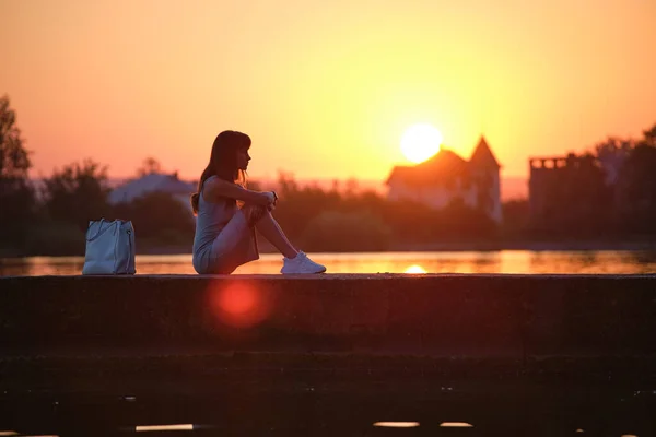 외로운 여자가 따뜻 한 저녁에 호수 옆에 앉아 있습니다. 고독 과 기분 전환의 개념 — 스톡 사진