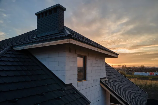 Casa inacabada con paredes de hormigón ligero aireado y marco de techo de madera cubierto con azulejos metálicos en construcción — Foto de Stock