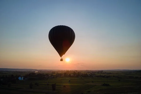 Vista aérea de un gran globo aerostático volando sobre el campo rural al atardecer —  Fotos de Stock