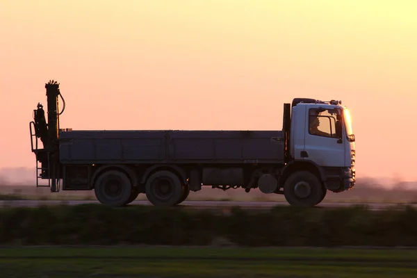 Carga caminhão basculante dirigindo na estrada transportando mercadorias à noite. Conceito de transporte e logística de entrega — Fotografia de Stock