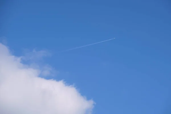 Entfernte Passagierflugzeuge fliegen in großer Höhe am blauen Himmel mit weißen Wolken, die Rauchspuren von Kondensstreifen hinterlassen. Flugreisekonzept — Stockfoto