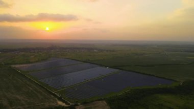Günbatımında temiz elektrik enerjisi üretmek için birçok sıra güneş fotovoltaik paneli bulunan sürdürülebilir büyük elektrik santralinin havadan görünüşü. Sıfır emisyon kavramı ile yenilenebilir elektrik