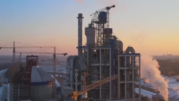 Vista aérea de la fábrica de cemento con alta estructura de planta de hormigón y grúa torre en el área de producción industrial por la noche. Fabricación y concepto de industria global — Vídeos de Stock