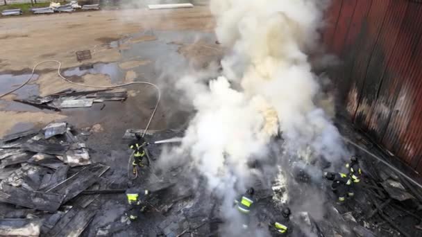 Luchtfoto van brandweerlieden die vechten met vuur in de buurt van oude fabrieksbiulding in industriegebied — Stockvideo