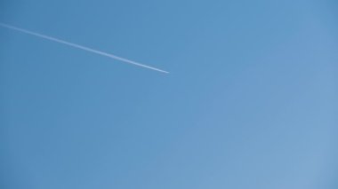 Mesafeli yolcu jet uçağı açık mavi gökyüzünde yüksek irtifada uçarken ardında beyaz duman izi bırakıyor. Hava taşımacılığı kavramı