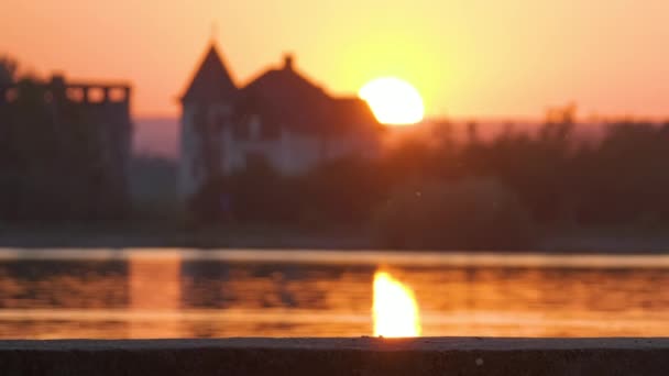 Silueta borrosa oscura de casas suburbanas frente al agua del lago al atardecer brillante — Vídeos de Stock