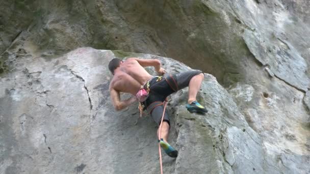 En beslutsam klättrare som klättrar uppför en brant mur av klippiga berg. Sportsmannen övervinner svår väg. Engagera sig i extrema sporter och bergsklättring hobby koncept — Stockvideo