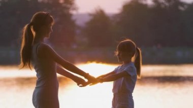 Mutlu anne ve kız el ele tutuşup akşamları yaz parkında eğleniyorlar. Aile sevgisi ve ilişki kavramı