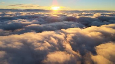 Yükseklerden gökyüzü manzarası. Akşamları yoğun, kabarık kümülüs bulutları uçuşuyor. Uçak penceresinden gün batımı inanılmaz.