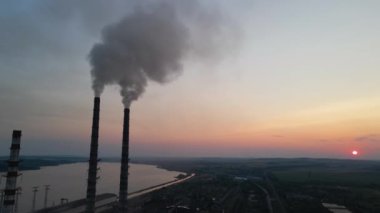 Kara dumanlı yüksek boruların hava görüntüsü gün batımında atmosferi kirletiyor. Fosil yakıt kavramına sahip elektrik enerjisi üretimi