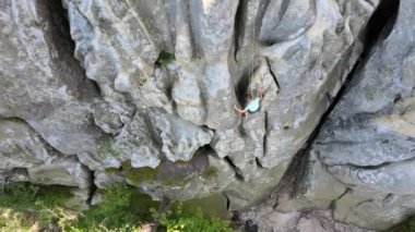 Küçük çocuk kayalık dağın dik duvarından aşağı iniyor. Çocuk tırmanışçı zorlu rotayı aştı. Ekstrem spor konseptine dalmak