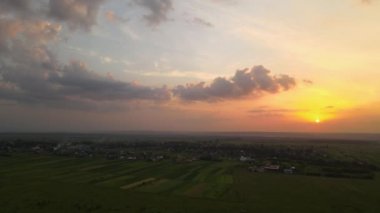 Yeşil ekili tarlaların, büyüyen ekinlerin ve parlak yaz akşamlarında uzak köy evlerinin hava manzarası.