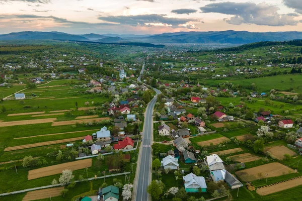 Vista aérea del paisaje de las casas de la aldea y los campos agrícolas cultivados verdes distantes con cultivos en el día brillante del verano — Foto de Stock