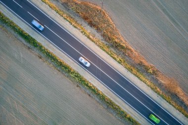 Gün batımında hızlı giden arabalarla şehirlerarası yol manzarası. Akşamları otoban trafiğinin insansız hava aracı görüntüsü
