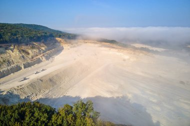 Kazı araçları ve çöp kamyonları ile inşaat endüstrisi için kireçtaşı malzemelerinin açık çukur madenciliğinin hava görüntüsü