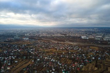 Bulutlu havalarda kırsal evlerin ve şehrin yerleşim alanındaki yüksek katlı apartmanların havadan görünüşü
