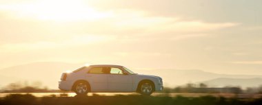 Gün batımında şehir içi yolda hızlı giden bir araba. Akşamları otoyol trafiği