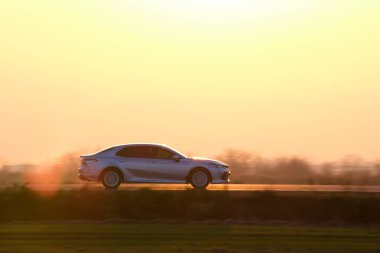 Gün batımında şehir içi yolda hızlı giden bir araba. Akşamları otoyol trafiği